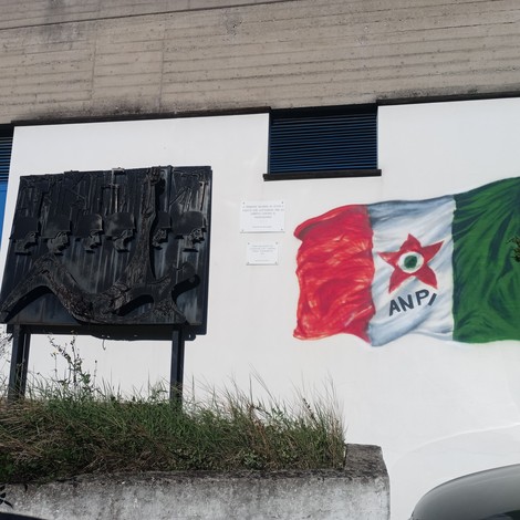 Monumento ai caduti per la Libertà, con elementi simbolici e bandiera dell'ANPI raffigurata.