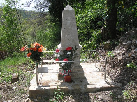 Cippo commemorativo con fiori, dedicato a Ghiribelli, Malossi e Tompetrini, immerso nella natura.