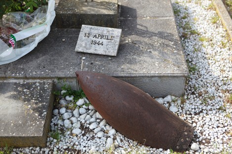 Monumento agli operai fucilati con un basamento in pietra e un proiettile arrugginito sul terreno.