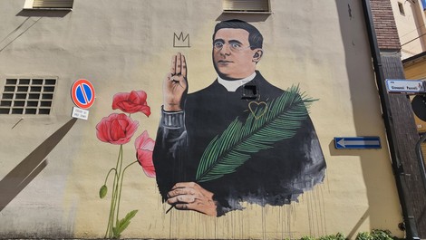 Murale colorato con un uomo che tiene una palma e fiori, decorato con simboli stilizzati.