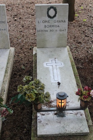 Tombe perpetue dei caduti per la Libertà, con fiori e lume, in un contesto memoriale solenne.