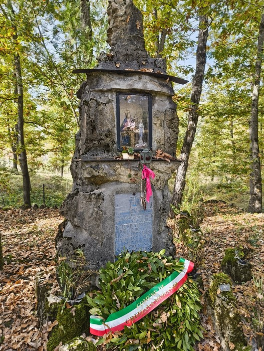 Monumento dedicato ai caduti, immerso nella natura di Ca' Boschetto, con vegetazione e commemorazioni.