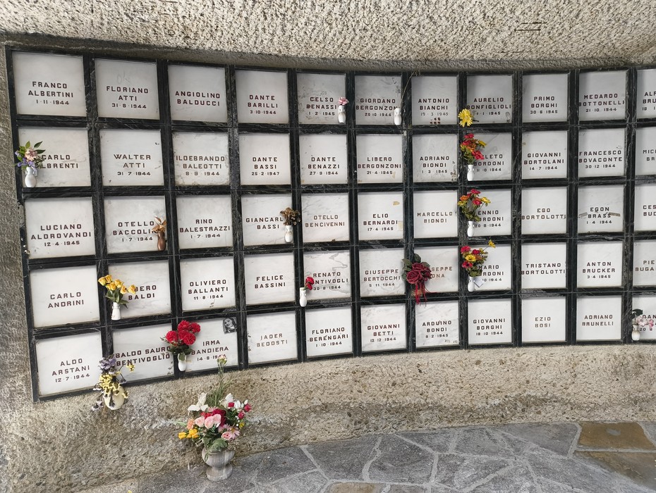 Monumento Ossario dei caduti partigiani, con lastre commemorative e fiori commemorativi.