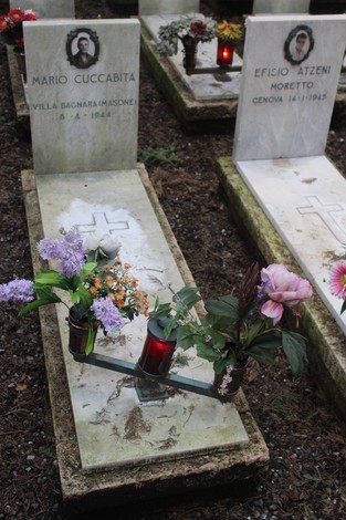 Tombe di caduti per la libertà, decorate con fiori e candele in un cimitero commemorativo.