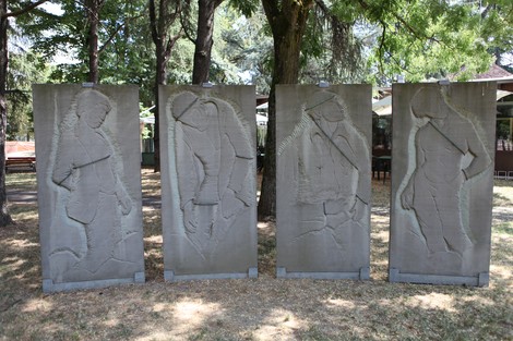 Monumento ai Martiri del Panaro, composto da quattro lastre scolpite immerse nel verde.