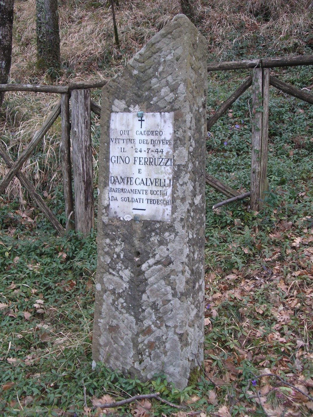Cippo commemorativo dedicato a Gino Ferruzzi e Dante Calvelli, situato in un'area naturale.