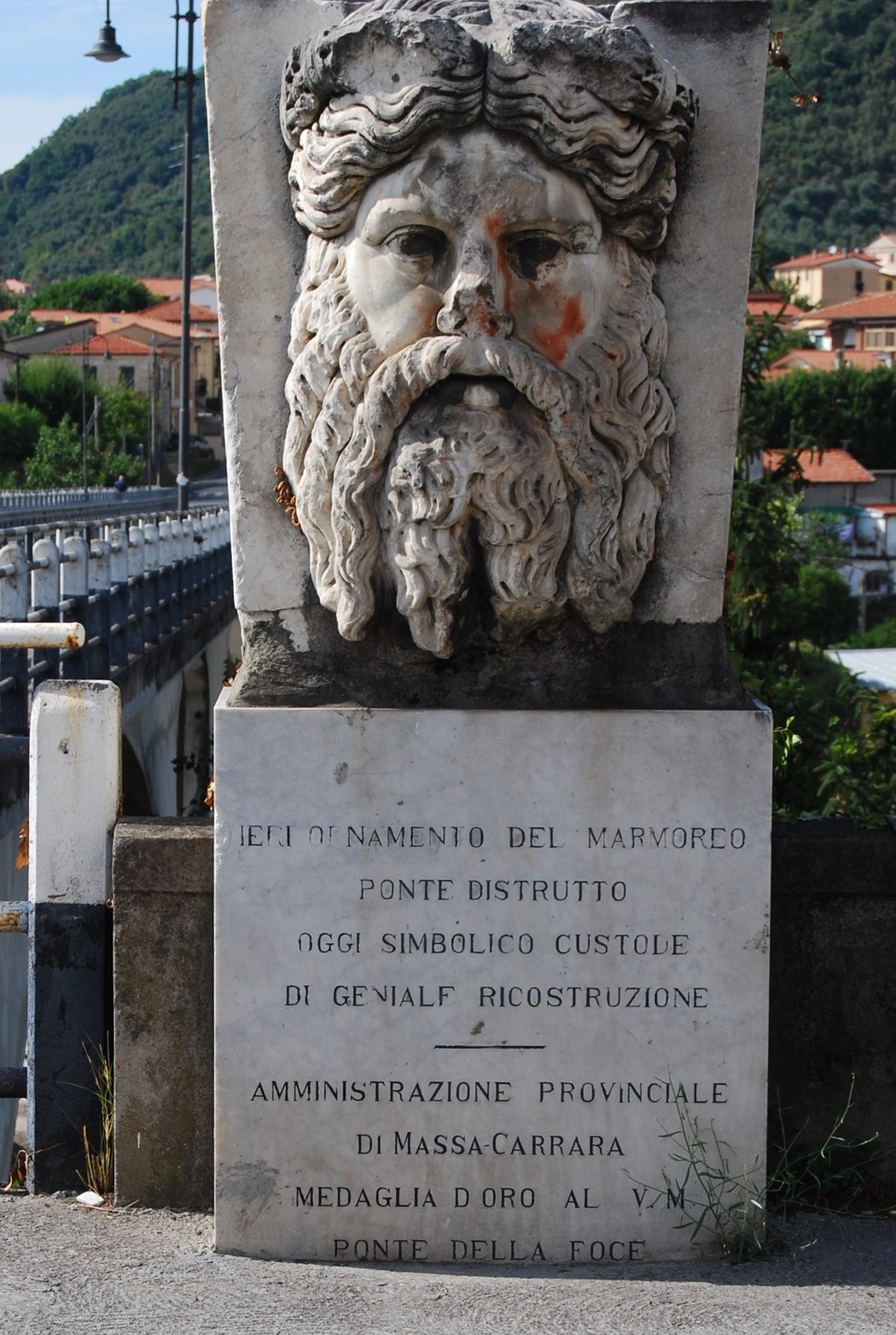 Lapide commemorativa sul ponte Frigido, simbolo di ricostruzione, con affreschi in marmo e dettagli storici.