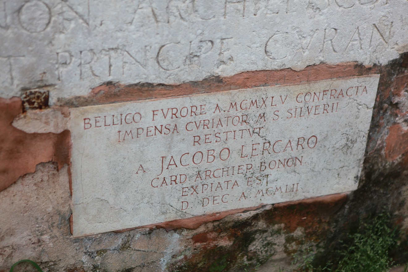 Lapide commemorativa per la ricostruzione di una croce, con iscrizioni storiche e decorazioni.