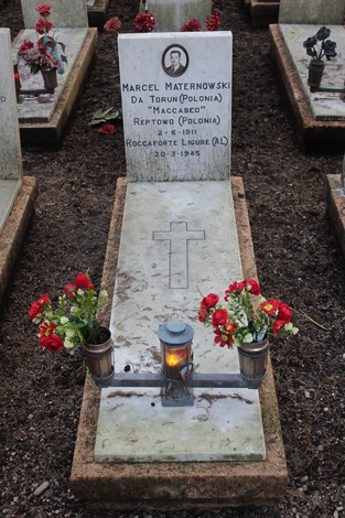 Tombe di caduti per la Libertà con decorazioni floreali e lumini commemorativi in un cimitero.