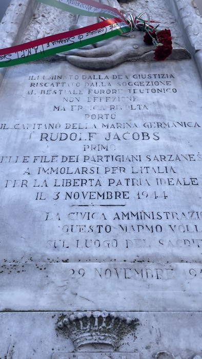 Lapide commemorativa a Rudolfe Jacobs, decorata con un nastro tricolore, in onore dei partigiani sarzanesi.