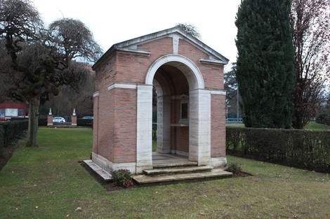 Cappella monumentale nel Cimitero di guerra del Commonwealth, circondata da verde e alberi.