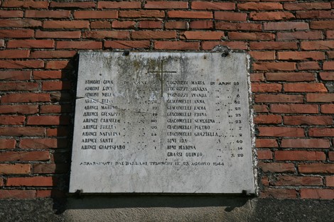 Lapide commemorativa della Casa Simoni, con nomi e date di ricordo. Edificio in mattoni rossi.