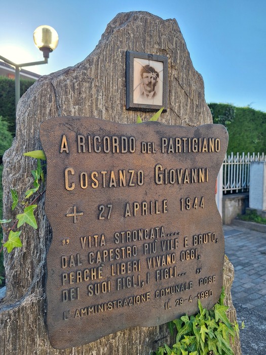 Cippo commemorativo dedicato al partigiano Costanzo Giovanni, con iscrizioni in memoria della sua vita e sacrificio.