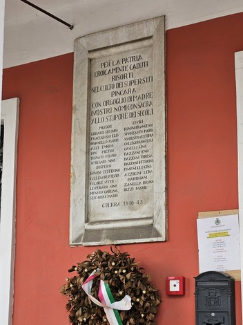 Lapide commemorativa ai caduti della guerra 1940-45, incastonata in una parete colorata.
