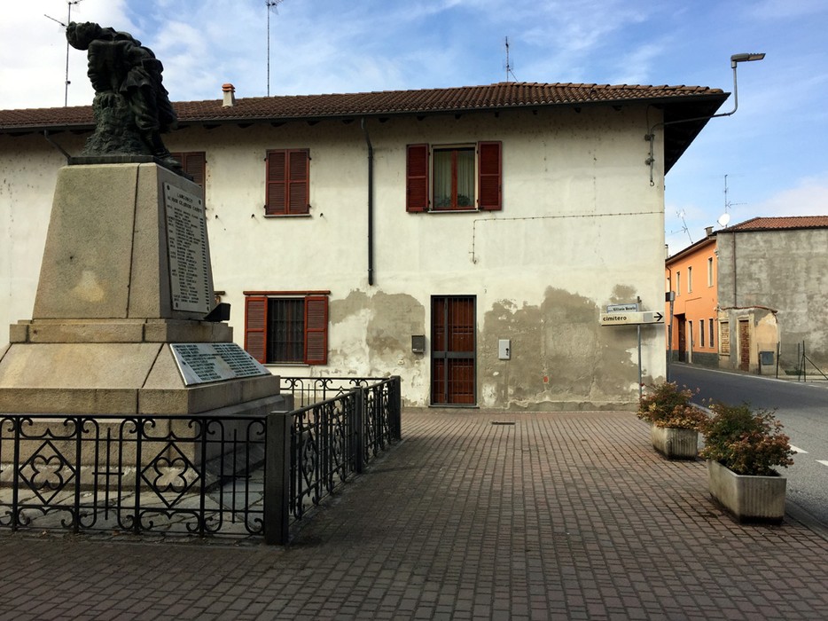 Monumento ai caduti di Langosco, situato in un'area pubblica con edifici storici sullo sfondo.