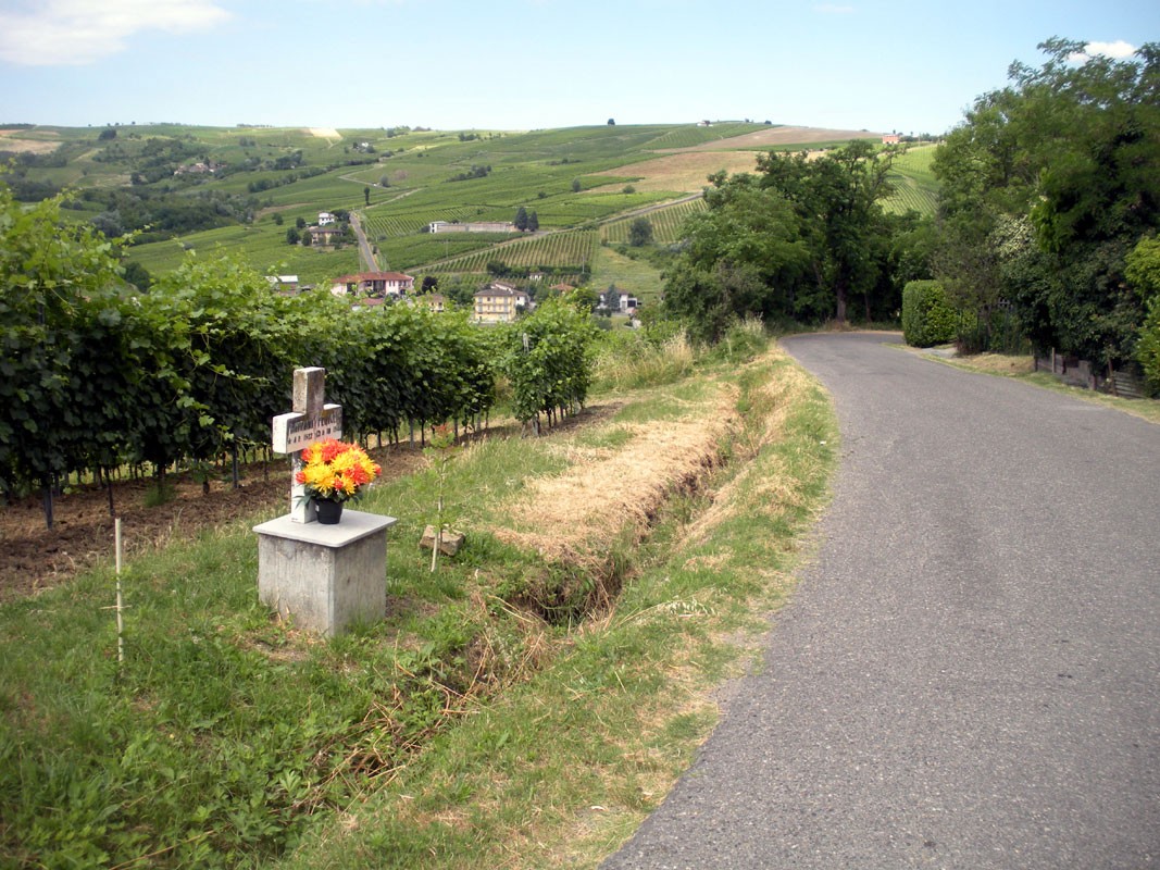 Croce a Battaini in un paesaggio collinare, con vigneti e una strada serena che si snoda tra i campi.