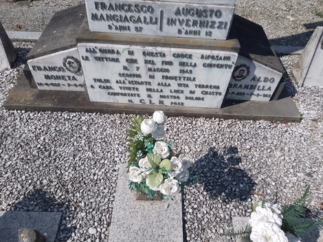 Tomba commemorativa dei martiri del 7 maggio 1945, con decorazioni floreali e lapidi in marmo.