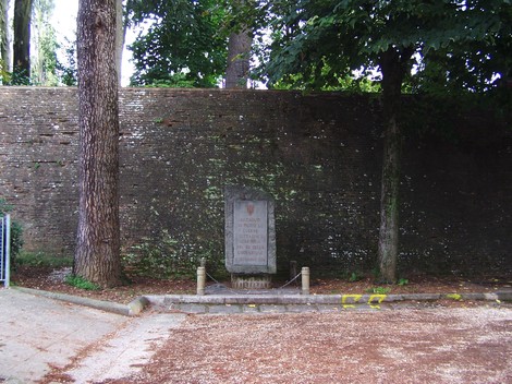 Cippo del cinquantenario, monumento commemorativo incastonato tra alberi e mura storiche.