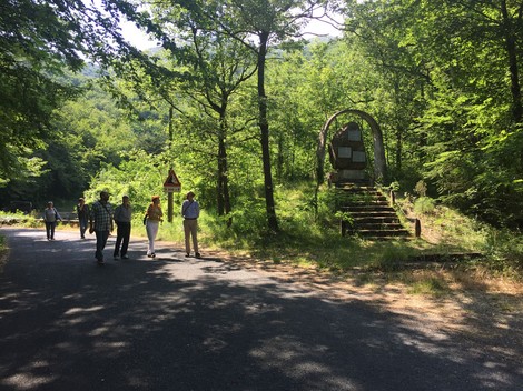Monumento ai partigiani immerso nel verde, con visitatori in cammino lungo la strada.