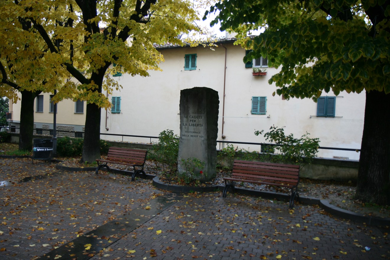 Monumento del ventennale, circondato da alberi e panchine, in un'atmosfera autunnale.