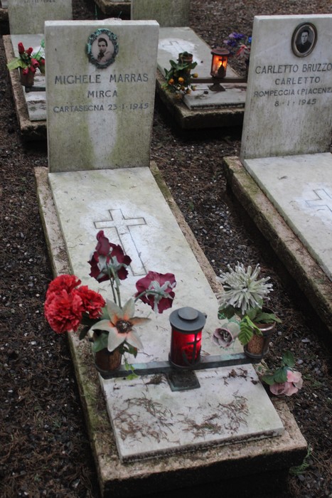 Tombe decorate con fiori e candele in memoria dei caduti per la libertà, simbolo di rispetto e commemorazione.