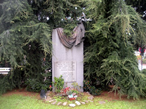 Monumento ai Martiri della Liberazione di Pinarolo Po, circondato da alberi e fiori, commemorativo e suggestivo.