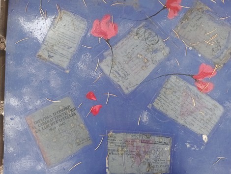 Una superficie blu con foglie rosse e documenti antichi parzialmente visibili.
