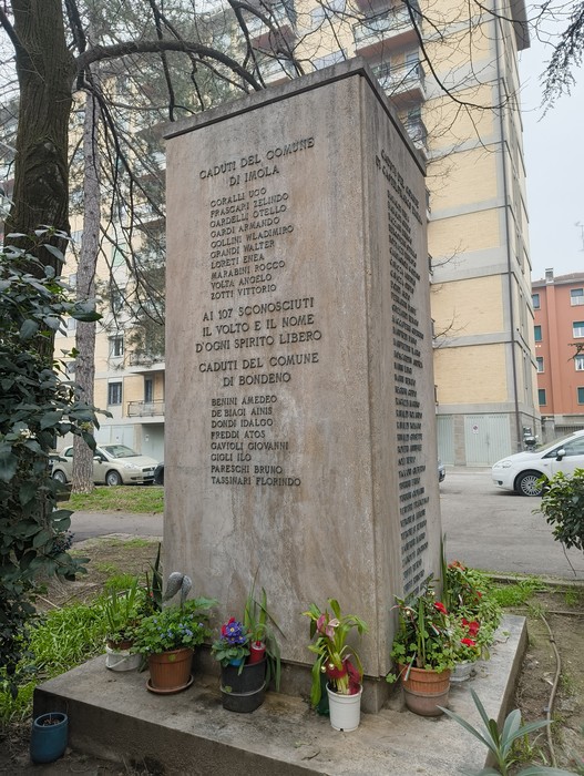 Monumento ai partigiani uccisi a San Ruffillo, commemorazione con nomi e fiori in un contesto urbano.