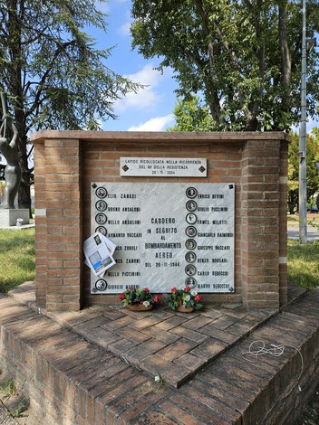 Monumento commemorativo dedicato alle vittime del bombardamento, con nomi incisi e decorazioni floreali.