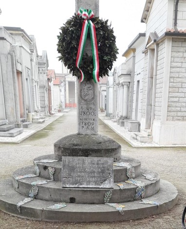 Lapide commemorativa in ricordo dei caduti nei lager, decorata con una corona e simboli italiani.