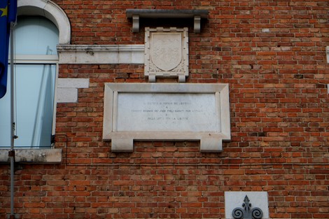 Lapide commemorativa in memoria dei caduti, situata su una facciata in mattoni.