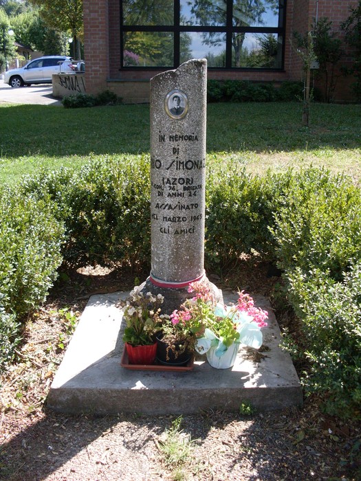 Cippo commemorativo dedicato a Simonazzi, con fiori e iscrizioni in memoria.