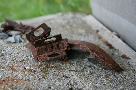 Resti di un cippo a Morasco, evidenziando la trama del metallo arrugginito su una superficie di pietra.
