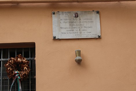 Lapide commemorativa dedicata al partigiano Lucarno Ezio, su facciata di un edificio storico a Lucarno.
