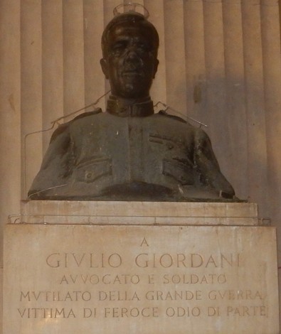 Busto in bronzo di Giordani, con iscrizioni commemorative su una base di pietra, collocato su sfondo architettonico.