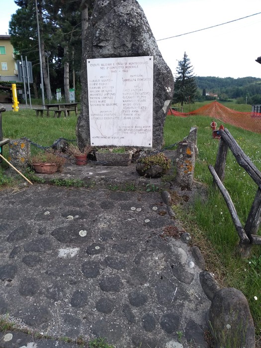 Monumento ai caduti di Montecorone, situato in un'area verde circondata da alberi e una recinzione in legno.