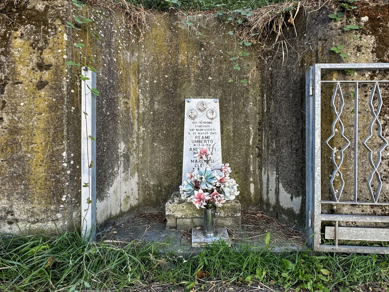 Cippo commemorativo dedicato a Marchesi, Andreotti e Reami, situato in un'area verde contemplativa.