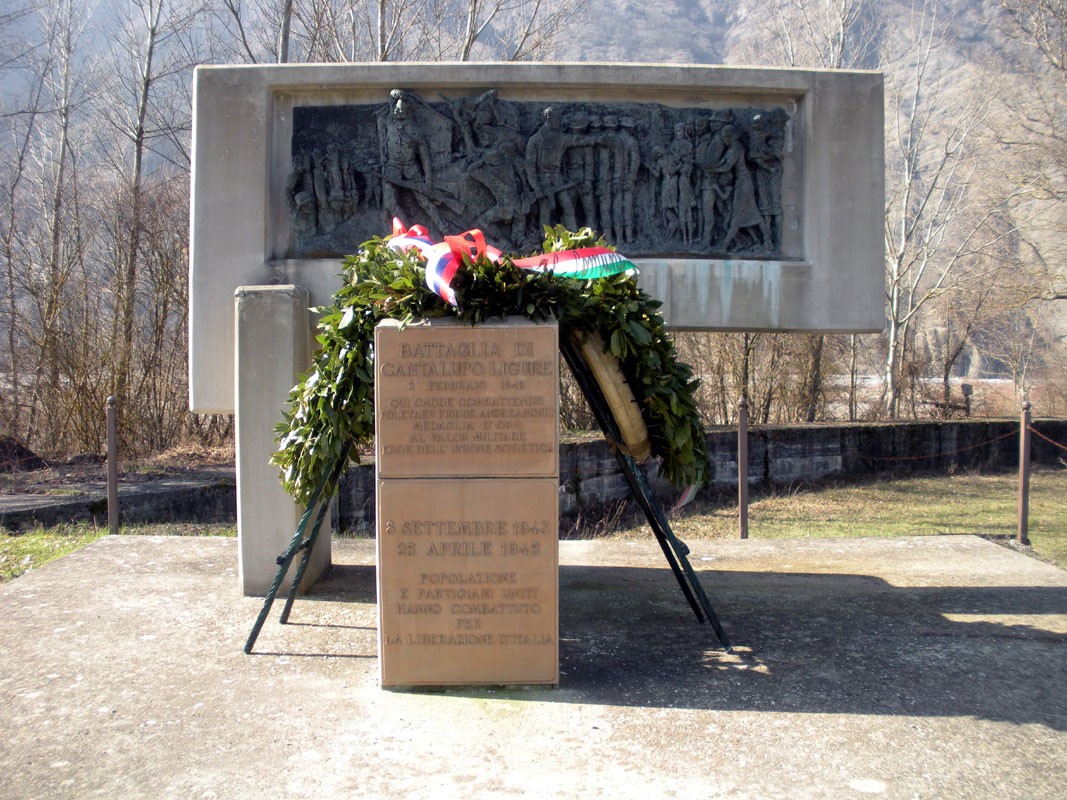 Monumento commemorativo della battaglia di Cantalupo Ligure, con una corona di fiori e iscrizioni memoriali.
