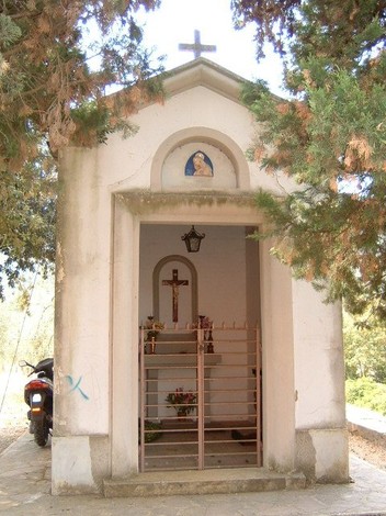 Cappella di Massa dei Sabbioni, un luogo di culto immerso nella natura, con una semplice facciata e decorazioni religiose.