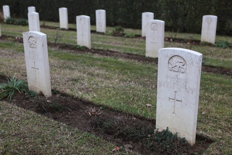 Cimitero di guerra del Commonwealth con lapidi bianche disposte ordinatamente su un prato curato.