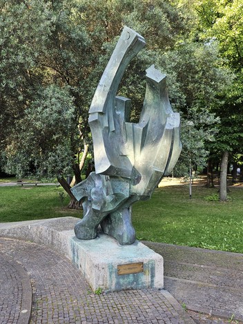 Scultura astratta del "Monumento alla Resistenza" immersa nel verde, simbolo di commemorazione storica.