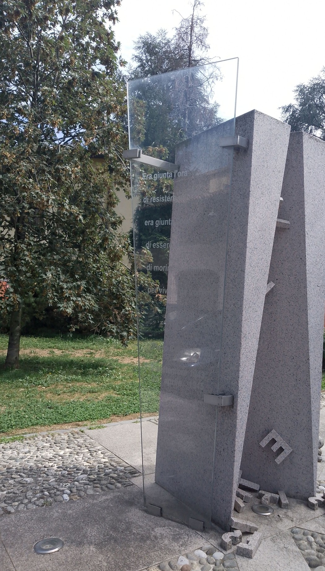 Monumento alla Resistenza, struttura moderna in pietra con dettagli trasparenti e ambiente verde circostante.