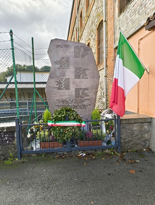Monumento commemorativo dedicato agli uccisi della Botte di Pioppe, con bandiera italiana e decorazioni floreali.