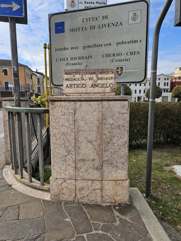 Lapide commemorativa di Artico Angelo situata in una zona pubblica, con segnali informativi nei dintorni.