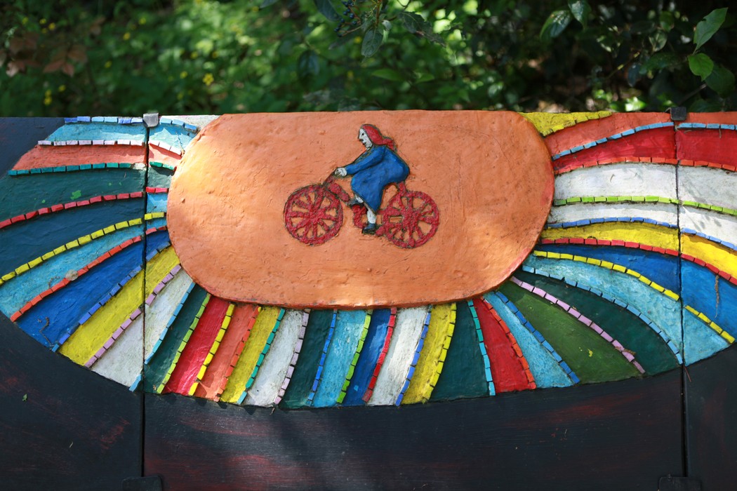 Monumento delle 128 partigiane con decorazioni colorate e figura di una ciclista su sfondo arcobaleno.