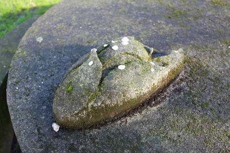 Monumento alla Resistenza con una scultura di pietra, immerso nella natura e decorato da piccoli fiori.
