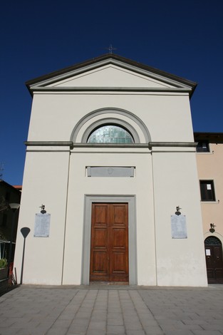 Lapide commemorativa ai caduti di Montalbano, situata davanti a un edificio sacro, cielo blu sullo sfondo.