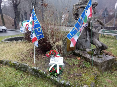 Lapide commemorativa dedicata a Grazzini, adornata con bandiere e fiori, situata in un'area pubblica.