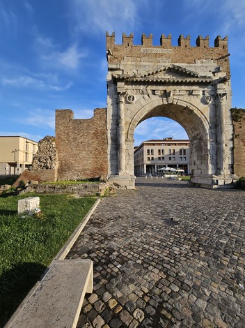 Cippo a Cenci, uno storico arco monumentale con dettagli architettonici, immerso in un contesto urbano e naturale.