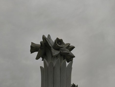 Monumento ai soldati sudafricani, con una scultura di fiori su sfondo nuvoloso.